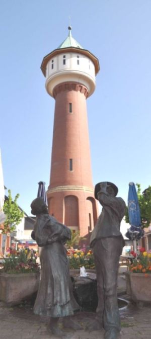 Wasserturm mit Bronzefiguren im Vordergrund